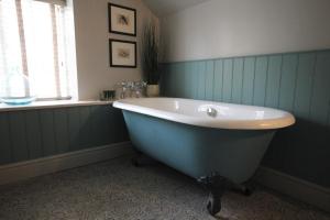 uma banheira na casa de banho com uma janela em The Ship Hotel em Brancaster