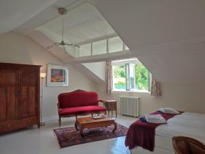 - une chambre avec un lit et une chaise rouge dans l'établissement Château du Pommoy, à Roussillon-en-Morvan