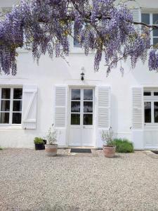 Maison blanche avec volets blancs et fleurs violettes dans l'établissement Château du Pommoy, à Roussillon-en-Morvan