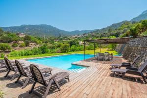 a wooden deck with chairs and a swimming pool at Es Port Estellencs in Estellencs