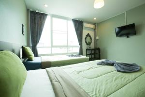 a hotel room with two beds and a television at White Monkey Guesthouse in Phetchaburi