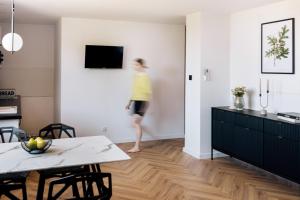 a woman is walking in a living room at Apartamenty Koziołek in Srebrna Góra
