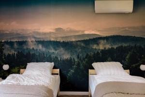 een slaapkamer met 2 bedden en een muurschildering van een bos bij Apartamenty Koziołek in Srebrna Góra