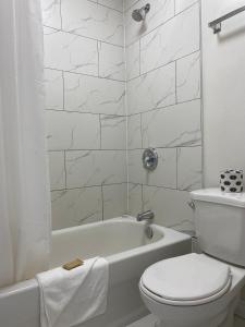 a white bathroom with a toilet and a bath tub at Apollo Motel in Kapuskasing
