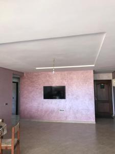 Habitación con pared de color rosa y TV de pantalla plana. en Appartement a louer avec piscine-Bouznika, en Rabat