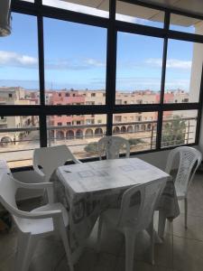 mesa y sillas en una habitación con ventana grande en Appartement a louer avec piscine-Bouznika, en Rabat