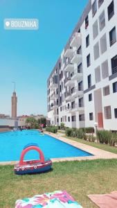 una piscina con un barco rojo frente a un edificio en Appartement a louer avec piscine-Bouznika, en Rabat