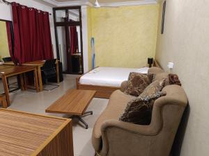 a room with a bed and a couch and a table at Sarada Hôtel in Ouagadougou