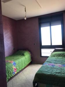 1 dormitorio con 2 camas y ventana en Appartement a louer avec piscine-Bouznika, en Rabat
