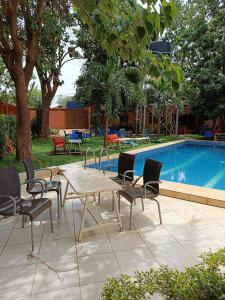 a patio with a table and chairs next to a pool at Sarada Hôtel in Ouagadougou
