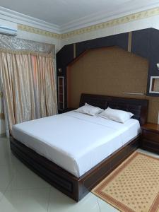 una camera da letto con un grande letto con lenzuola bianche di Sarada Hôtel a Ouagadougou