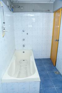 a white bath tub in a bathroom with blue tiles at Sakura Hill in Kandy