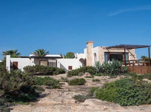 uma casa no topo de uma colina com arbustos em El Penasco em Sant Ferran de Ses Roques