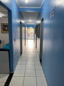 a hallway with blue walls and a white tile floor at Pousada o Paraiso in Camamu