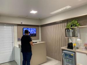 Un homme debout devant un comptoir devant une télévision dans l'établissement Hotel Haki, à Patos