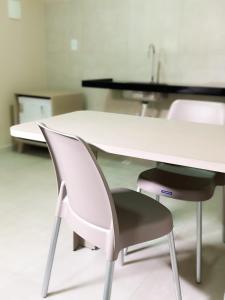 twee witte stoelen rond een witte tafel en een bureau bij Hotel Haki in Patos