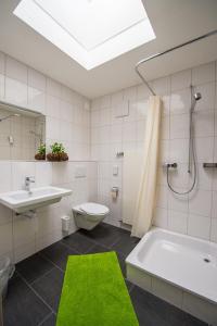 baño con lavabo, bañera y alfombra verde en Jugendherberge Romanshorn, en Romanshorn