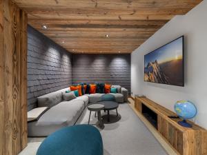 a living room with a couch and a tv at Chalet Courchevel 1550, 7 pièces, 14 personnes - FR-1-562-47 in Courchevel