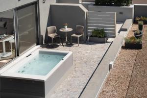 a hot tub on a patio with a table and chairs at Athens Hill Luxury Apartments in Athens