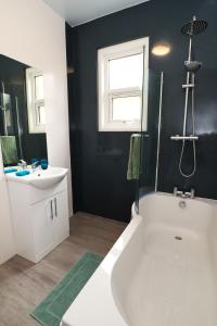 a bathroom with a white tub and a sink at Seafront House with balcony in Eastbourne