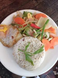 une plaque de nourriture avec du riz et des légumes sur une table dans l'établissement Happy Homestay - Local Vibe, à Phumĭ Puŏk Chăs