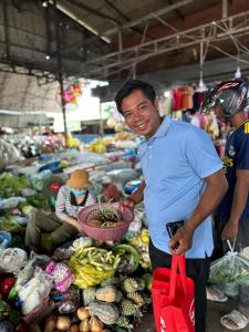 un homme détenant un panier de légumes sur un marché dans l'établissement Happy Homestay - Local Vibe, à Phumĭ Puŏk Chăs