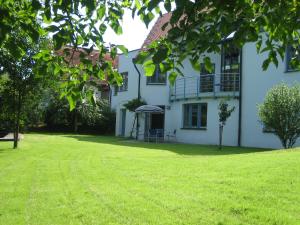 Una gran casa blanca con un patio de césped. en Ferienwohnung BAYERNRING, en Breitenbrunn