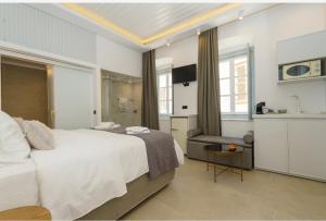 La Vie Hydra Luxury Suites في هيدرا: غرفة نوم بسرير واريكة وطاولة