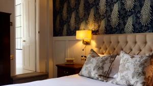 a bedroom with a bed with pillows and a lamp at Simonstone Hall Hotel in Hawes