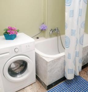 a bathroom with a washing machine and a bath tub at Zeta's vintage garden house in Sparti