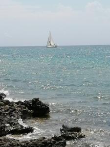 a sail boat in the ocean with a rocky beach at To Kyma in Skala Kallirakhis