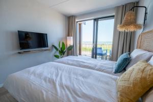 a bedroom with two beds and a tv and a balcony at Soal Beach Resort in Workum