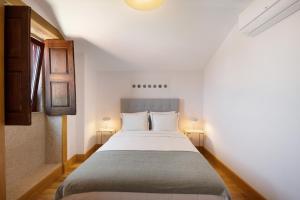 - une chambre avec un grand lit blanc et deux lampes dans l'établissement Casa do Outeiro, à Guilhabreu