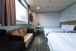 台北市にあるソーフー ホテルのベッド2台とソファが備わるホテルルームです。