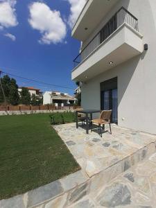 a patio with a table and a bench in front of a house at ACTA Luxury Rooms in Nikiti