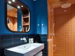 ein Badezimmer mit einem weißen Waschbecken und einem Spiegel in der Unterkunft 25hours Hotel Hamburg HafenCity in Hamburg