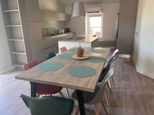 a dining room table with chairs and a kitchen at Gîte Anna in Chavanay