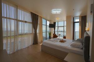 a bedroom with a large bed and large windows at RUMI Hotel in Batumi