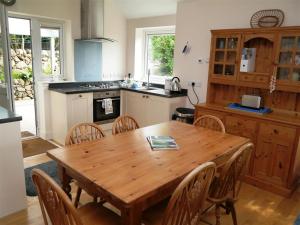 a kitchen with a wooden table and wooden chairs at Seabank Cottage in Rockcliffe