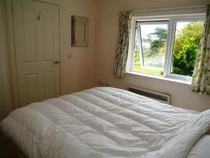 a bedroom with a large white bed in front of a window at Seabank Cottage in Rockcliffe