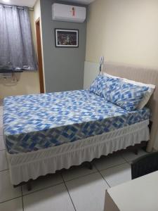 a bed with a blue and white comforter in a room at Hotel Kairos in Campina Grande