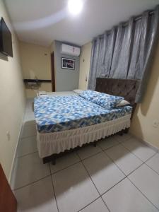 a bedroom with a bed with a blue comforter at Hotel Kairos in Campina Grande