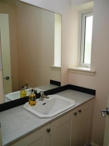 a bathroom with a white sink and a mirror at Seabank Cottage in Rockcliffe