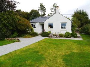 une maison blanche avec une pelouse et des chaises dans une cour dans l'établissement Seabank Cottage, à Rockcliffe