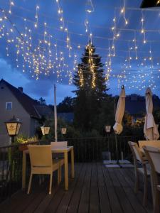 une terrasse avec une table, des chaises et des lampes à cordes dans l'établissement Parkhotel Forsthaus, à Tharandt