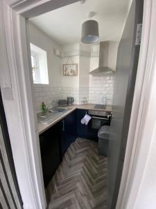 una pequeña cocina con armarios azules y fregadero en Blackpool Abode - Sunny Suite Apartment, en Blackpool