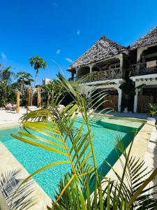 a swimming pool in front of a house at Olamanga Beach Villa in Jambiani