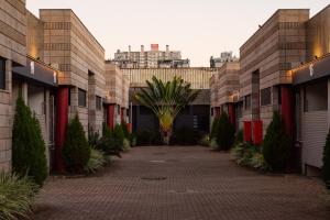 a courtyard with a palm tree between two buildings at Motel Vis à Vis POA in Porto Alegre