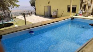 een zwembad met blauw water en een houten terras bij וילה פינתית עם נוף פאנורמי לכנרת in Nof Kinneret