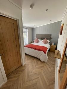 ペンブルックシャーにあるCanaston Waterside Lodgesのベッドルーム1室(ベッド1台、赤と白の毛布付)